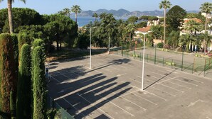 A tennis court with a clear view of the sea and mountains in the background.