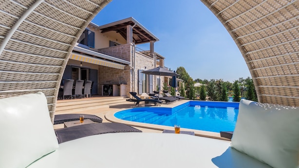 Ein Poolbereich mit Liegestühlen und Blick auf ein Haus mit Balkon.