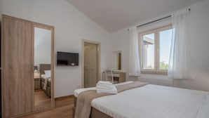 Ein Schlafzimmer mit Bett, Fernseher, Schreibtisch und Kleiderschrank.