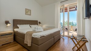 Ein Schlafzimmer mit einem Bett, Nachttischen, einem Hängehandtuchhalter und einem Balkon mit Tisch und Stühlen.