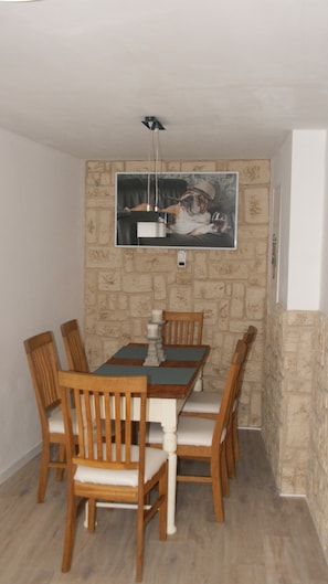 A dining area with a rectangular table and six chairs, a framed picture above, and a pendant light.