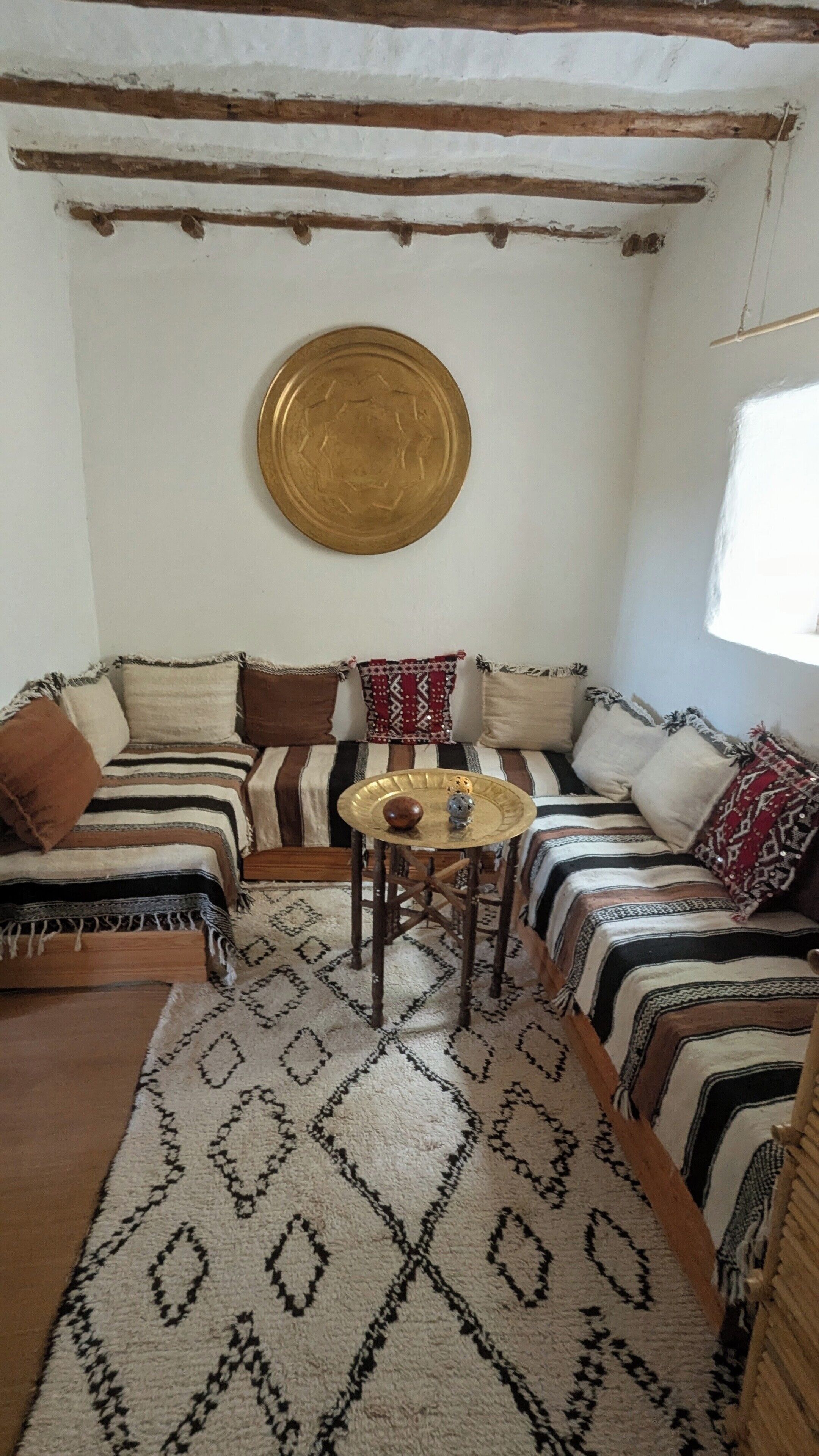 A room with a sofa set, a round table with a decorative plate, and a patterned rug.