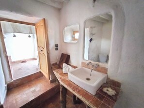 A bathroom with a white sink, a mirror, and a wooden door.