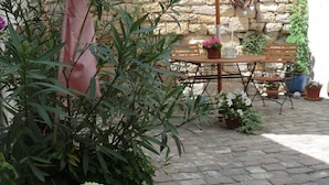 Eine Terrasse im Freien mit Holztisch und -stühlen, umgeben von Pflanzkübeln und einer Steinmauer.