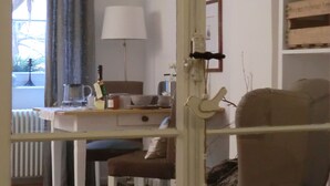 Ein Zimmer mit einem weißen Schreibtisch, einem Stuhl, einem Heizkörper, einer Lampe und einem Bücherregal.