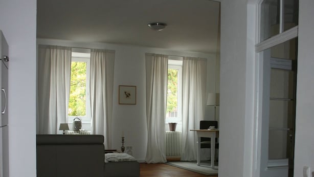 Eine moderne Küche mit Holzboden, einem eingebauten Backofen und einer weißen Arbeitsplatte.