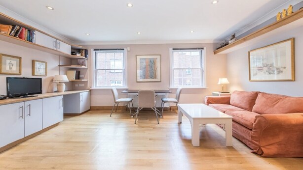 Uma sala de estar moderna com sofá, mesa de centro, televisão e área de jantar com cadeiras e mesa.