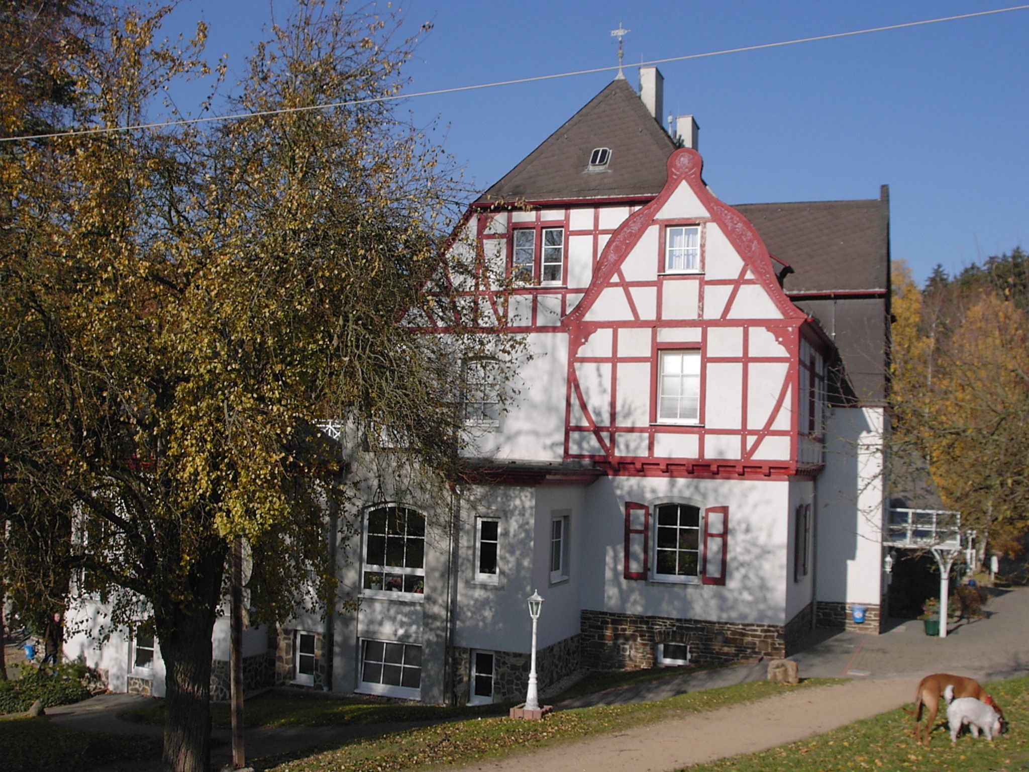 A traditional half-timbered house with a steep gabled roof, a stone foundation, and a small attached structure.