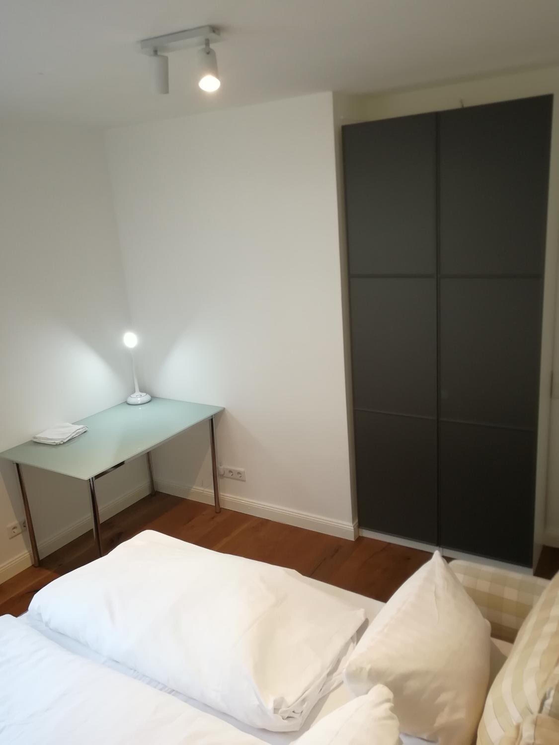 Un dormitorio con cama, escritorio y armario.
