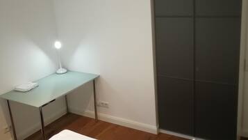 Un dormitorio con cama, escritorio y armario.
