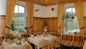 A dining area with a table set for four, a bench, and a view of the outdoors. - Waldhotel Forsthaus Remstecken (Koblenz)