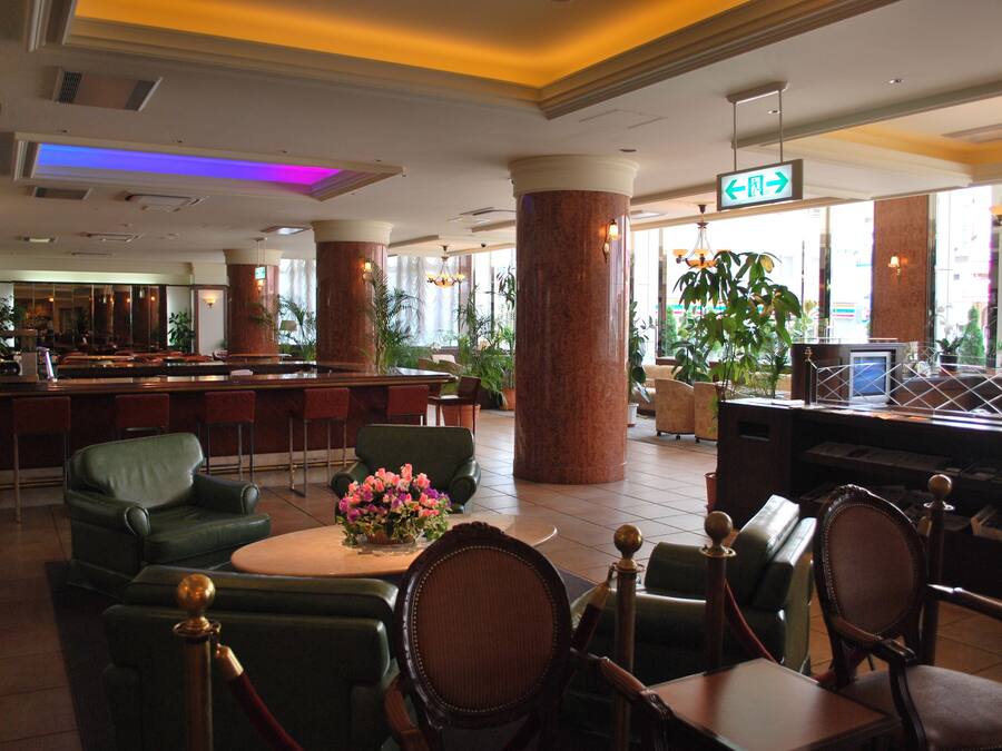 A hotel lobby with a bar area, seating arrangements, and large windows.