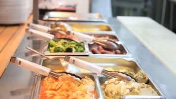 A buffet line with various food options, including pasta, chicken, and vegetables.