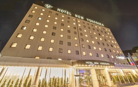 A multi-story hotel building with illuminated windows and a sign reading "HOTEL NEW YOKOSUKA".