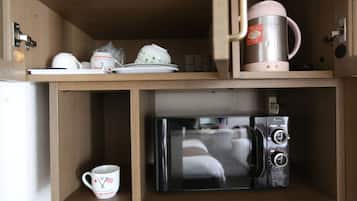 A kitchen area with a microwave, a coffee maker, and a cup.