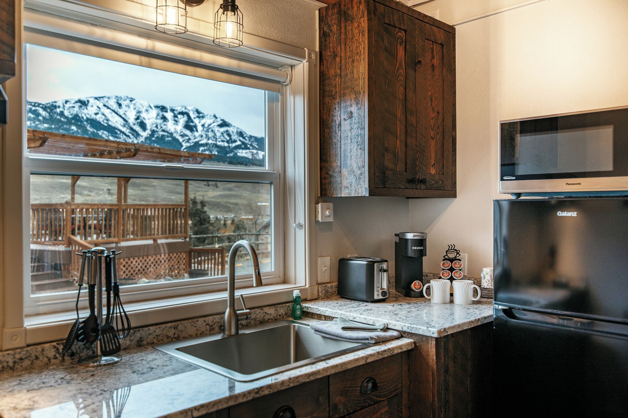Una cocina con vistas a las montañas, un fregadero, un tostador, una cafetera y un refrigerador.