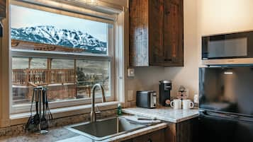 Una cocina con vistas a las montañas, un fregadero, un tostador, una cafetera y un refrigerador.