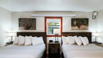 Habitación doble con dos camas, una ventana con vistas y dos cuadros de ciervos colgados en la pared.
