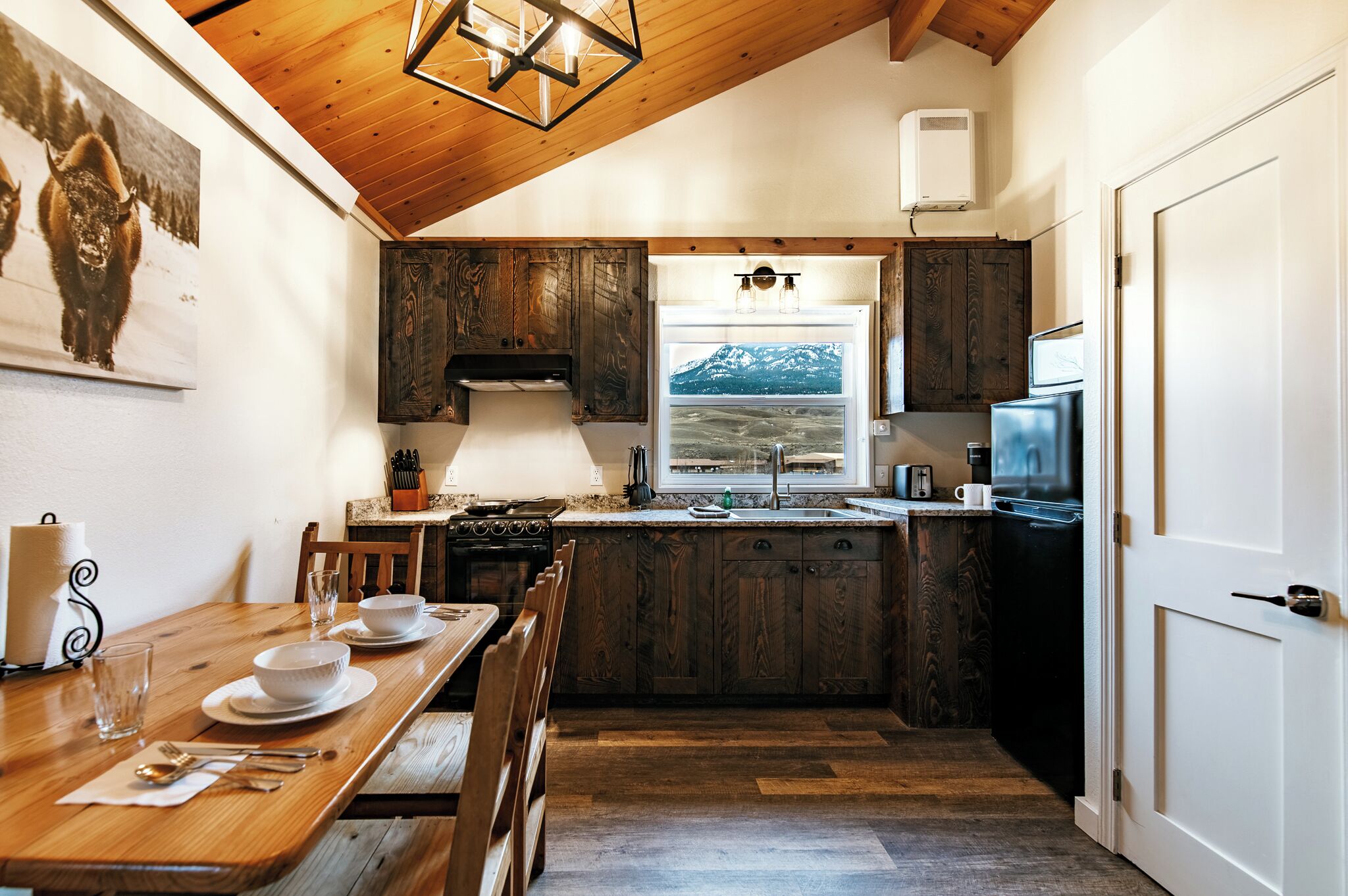 A kitchen with wooden cabinets, a stove, and a window with a mountain view.