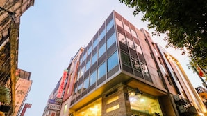 A modern building with multiple floors, large windows, and a prominent sign for a hotel. - Hotel Krishna Plaza (New Delhi)