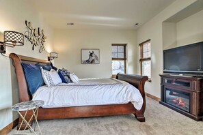 A bedroom with a wooden bed, a TV, a fireplace, and a wall-mounted artwork. - Winter Park Area Cabin, Hot Tub & Mountain Views! (Fraser)