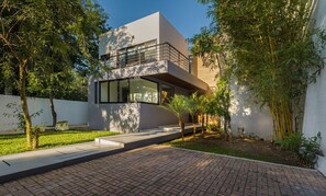 A modern two-story house with a flat roof, large windows, and a balcony. - Sara- Ultra-Lux 5-Bedroom Oceanfront with Infinity Pool (San Miguel de Cozumel)