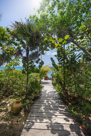 A wooden pathway leading to a seating area with a view of the sea.