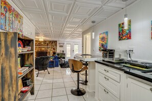 Une cuisine avec des meubles blancs, un tabouret de bar, une cuisinière et un mur en pierre.