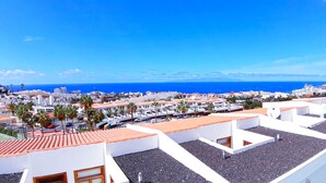 Una zona residencial costera con edificios blancos, tejados de tejas rojas y una vista despejada del mar.