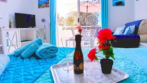 Una habitación con cama, sofá, mesa de comedor con sillas, televisor y ventana con vista al exterior.