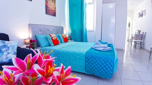 A modern bedroom with a bed, pillows, a nightstand, a lamp, and a window with curtains.