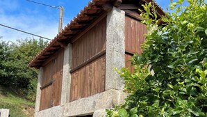 Un bâtiment rustique en pierre, doté d’une façade en bois, d’une entrée en pierre et d’un petit jardin agrémenté de feuillage verdoyant.
