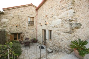 A stone building with a courtyard, outdoor seating, and potted plants.
