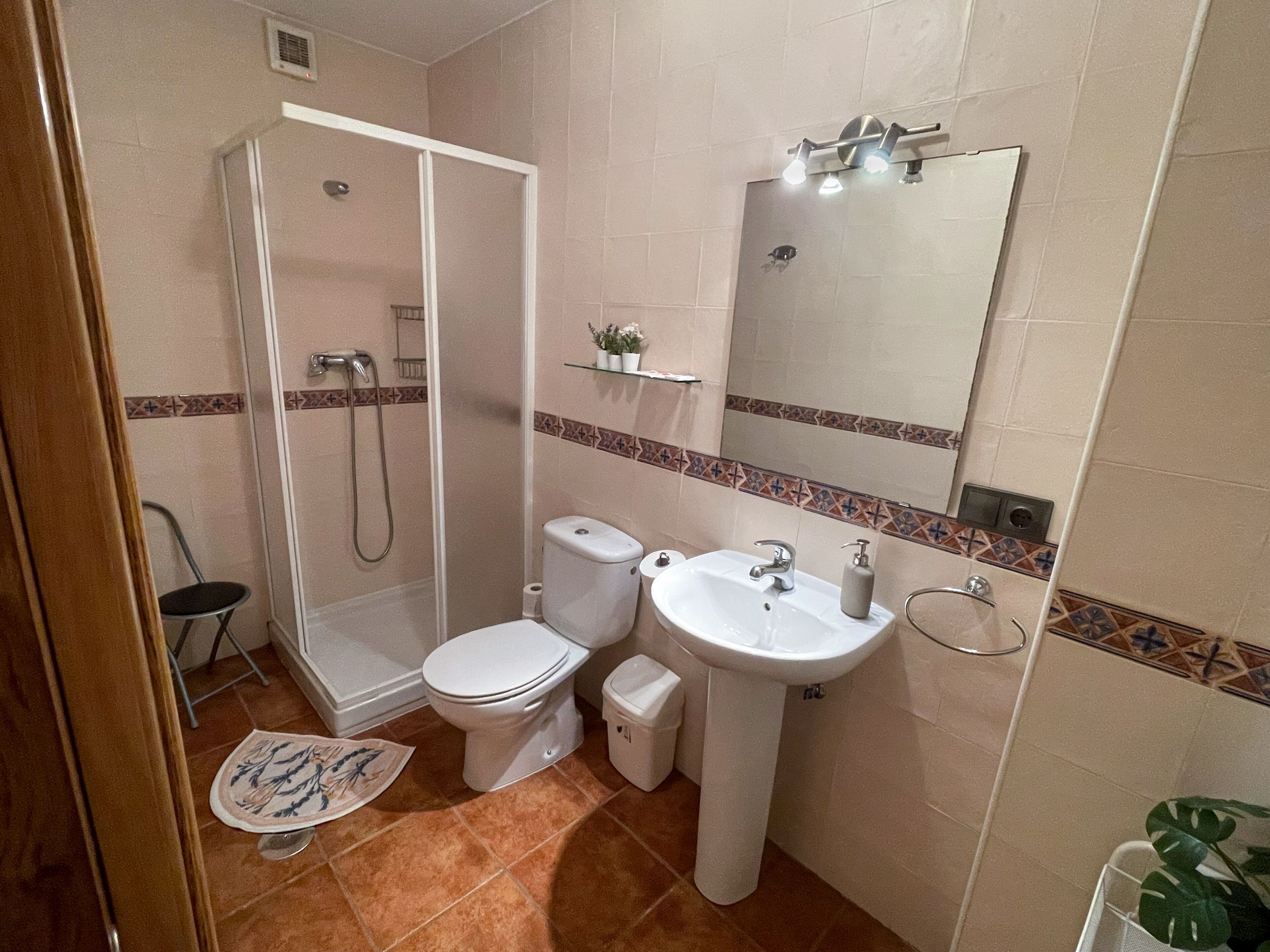 Ein Badezimmer mit Dusche, Toilette, Waschbecken und Spiegel.