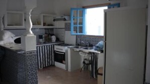 A compact kitchen with a stove, sink, and a window with blue shutters. - House / Villa - Guizen djerba (djerba)
