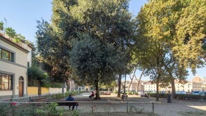 Ein Park mit Bänken, Bäumen und einem Gebäude im Hintergrund.