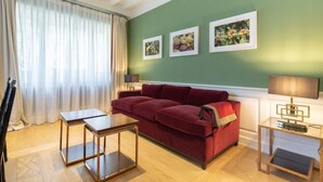 Ein Wohnzimmer mit einem roten Sofa, einem Holztisch, einer Lampe und gerahmten Bildern an der Wand.