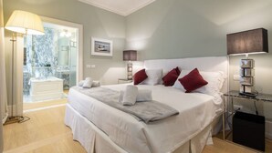 Ein geräumiges Schlafzimmer mit einem großen Bett, einem in Glaswänden gefassten Badezimmer und Blick auf einen Pool.