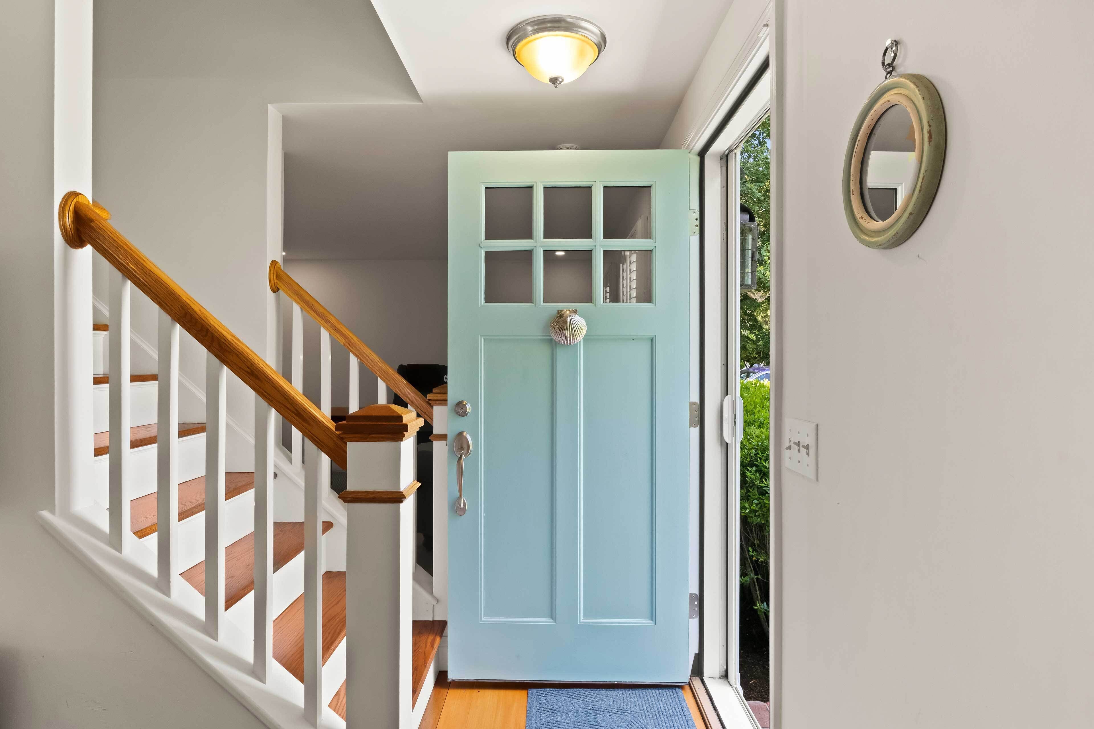A staircase with wooden handrails and a light blue door with glass panels.