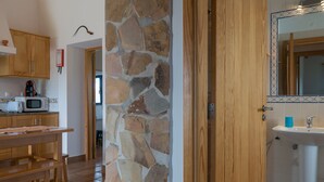 A kitchen with wooden cabinets, a stone wall, a wooden table, and a microwave. - Digne Blue Villa, Pool, BBQ (Rogil, Aljezur)