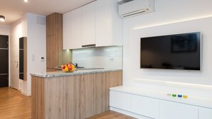 A modern kitchen with a wooden island, white cabinets, and a flat-screen TV mounted above the island. - Old Town, trendy Kazimierz, luxurious and spacious 2 bdrm, 2 bthrm, Apartment  (Kraków)
