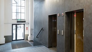 A modern elevator area with a tiled floor, a large window, and a door with a glass panel. - Old Town, trendy Kazimierz, luxurious and spacious 2 bdrm, 2 bthrm, Apartment  (Kraków)