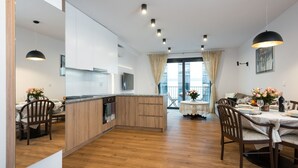 A modern kitchen with wooden cabinets, a central island, and a dining area with a round table and chairs. - Old Town, trendy Kazimierz, luxurious and spacious 2 bdrm, 2 bthrm, Apartment  (Kraków)