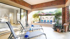 Un patio soleado con piscina, sillas de descanso y plantas en macetas.