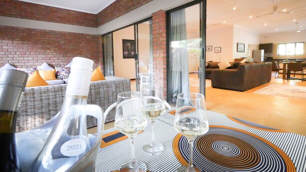 Una sala de estar moderna con pared de ladrillo, un sofá con cojines, un comedor con sillas y un ventanal grande.