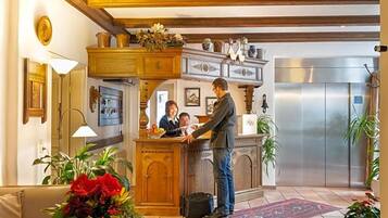 Een hotelhal met een receptiebalie, een bank en een lift.