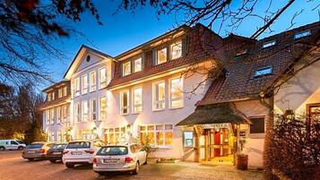 Een meerhoog hotel met een klassieke Europese architectuur, met een centrale ingang en een winkel op de begane grond.