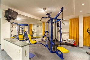 A gym with exercise equipment, a television, and a mirror. - Hotel Restaurant Grotehof (Minden)