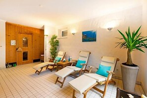 A room with wooden walls, a large potted plant, and three lounge chairs with cushions. - Hotel Restaurant Grotehof (Minden)
