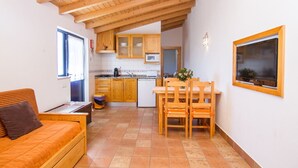 A compact kitchen with wooden cabinets, a dining table, and a sofa. - Digne Orange Villa, Pool, BBQ (Rogil, Aljezur)